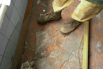 Close-up of legs in old military shoes on shards of glass.