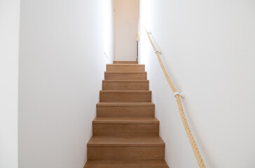 Staircase with white walls and a rope handrail