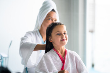 Mom Brushing Daughter Hair. Family Spa