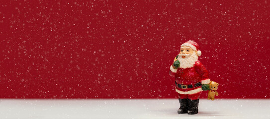 Panoramic scene for Christmas greetings with Santa Claus figurine holding teddy bear and other gifts