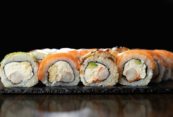 Sushi set Philadelphia roll with king prawn, smoked eel, salmon and cream cheese on a black background. Traditional Japanese cuisine. Asian food concept