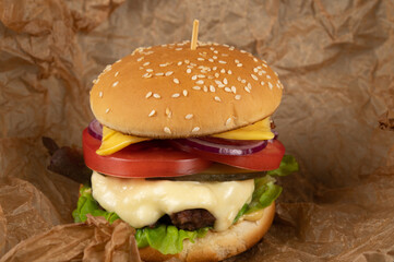 A toasted sesame bun hamburger with pickles and ripe tomatoes