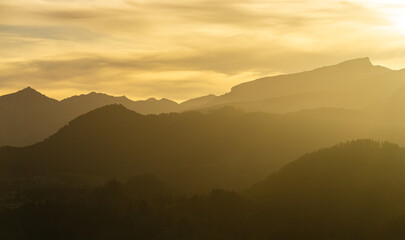Spectacular view of mountain ranges silhouettes with yellow sunlight. Sunset in Allgau, Germany, Alps.