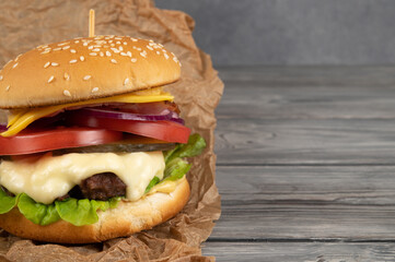 A toasted sesame bun hamburger with pickles and ripe tomatoes