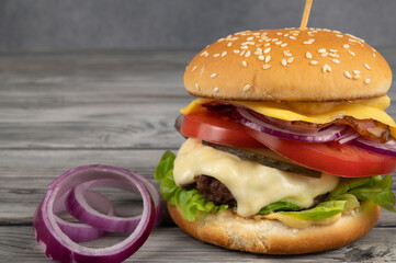 A toasted sesame bun hamburger with pickles and ripe tomatoes