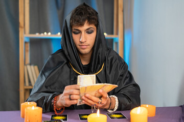 fortune teller man reading tarot cards on a table with candles.