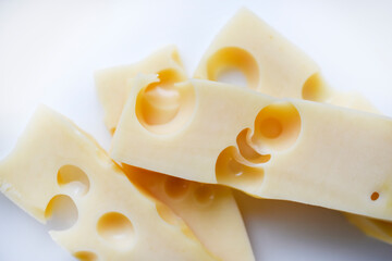 Pieces of yellow cheese with large holes on a white background. Delicious cheese close-up.