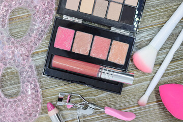 Pink-themed makeup flatlay on wood background