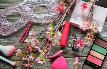 Pink-themed makeup flatlay on wood background