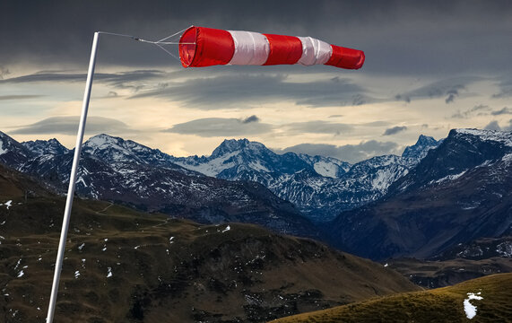 Striped Windbag and dark storm clouds over snow spotted mountains. Concept for creative business ideas. Allgau, Alps, Germany.