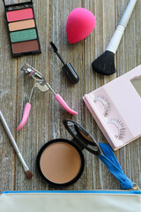 Pink-themed makeup flatlay on wood background