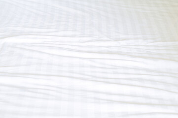 White wrinkled bedding sheet with pattern after guest's use was taken in hotel room with copy space, Untidy blanket background texture