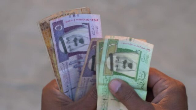 man counting Saudi Arab riyals, Saudi Arabia Currency