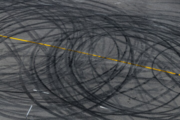 Tire track mark on asphalt tarmac road race track texture and background, Abstract background black tire tracks skid on asphalt road in racing circuit, Tire mark skid mark on asphalt road. © Darunrat