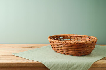 Empty wicker basket on wooden table with tablecloth over modern  background. Kitchen interior mock up for design and product display