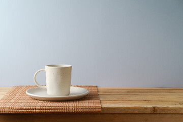 Coffee cup on wooden table over gray wall background.  Kitchen mock up for design and product...
