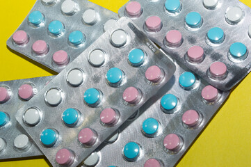 Multicolored pills on a yellow background.