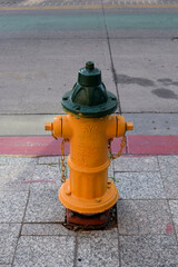 Bright yellow fire hydrant valve on a street with multi-colored stripes