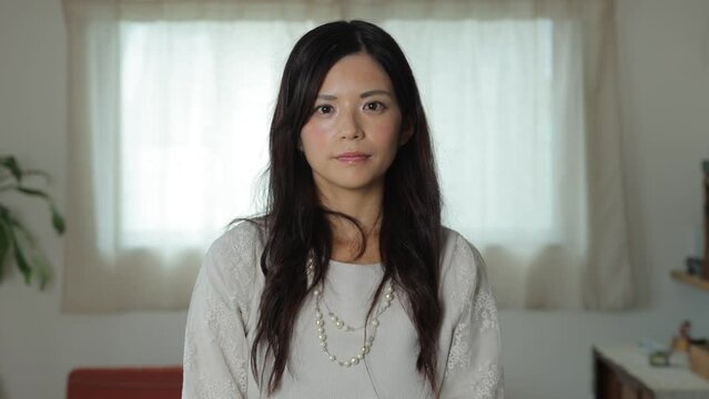 Beautiful Japanese woman opens her eyes and stares the camera. Emotionless, Still, Protest.