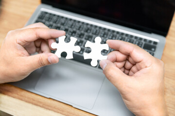 business man hold jigsaw puzzle to match and connection business partner economic with online internet laptop computer