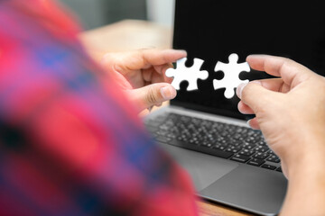 business man hold jigsaw puzzle to match and connection business partner economic with online internet laptop computer