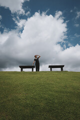 Happy young woman look at faraway when her relaxing in the park wiith clue sky and cloud