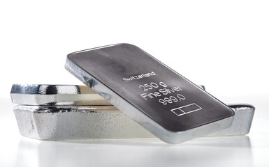 Minted silver bar weighing 250 grams against a background of a stack of various silver ingots....