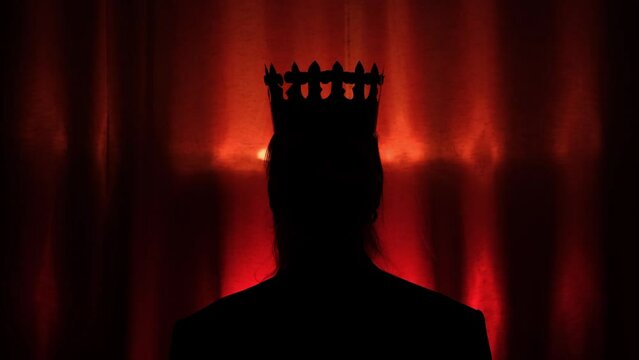Silhouette of coronation a person by the crown on dark red backgground with zoom in moving. Ceremony of coronation of queen or king in abstract form. Concept of success
