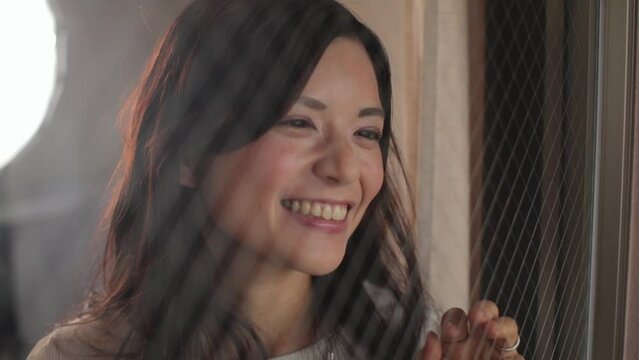 Japanese woman looks outside of the window. Emotion of happiness and joy. Slow-mo.