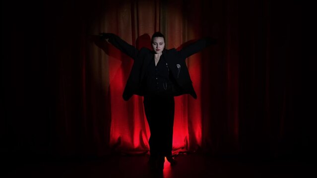 Elegant dancer, actress woman in enters the stage in a dark red background with circle light focusing on her