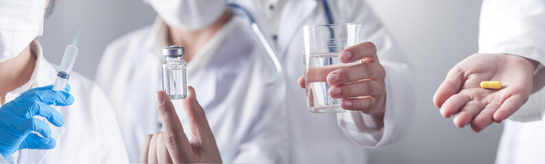 Doctor holding pill, syringe and a glass of water.
