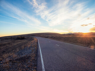 Empty mountain highway at sunset. Asphalt road and sky clouds at sunset.Road background.