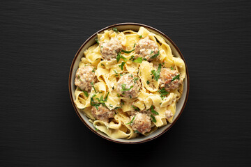 Homemade One-Pot Swedish Meatball Pasta in a Bowl on a black background, top view. Flat lay, overhead, from above. Close-up.