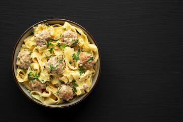 Homemade One-Pot Swedish Meatball Pasta in a Bowl on a black background, top view. Flat lay, overhead, from above. Space for text.