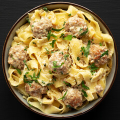 Homemade One-Pot Swedish Meatball Pasta in a Bowl on a black background, top view. Flat lay, overhead, from above. Close-up.