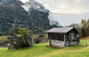 Fototapeta na wymiar Traditional Swiss architecture and wooden alpine houses in the autumn environment of mountain pastures and mixed forests in the Taminatal river valley, Vättis - Canton of St. Gallen, Switzerland