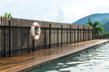 White-red lifebuoy hanging on the wall near pool in Chiang Mai, Thailand