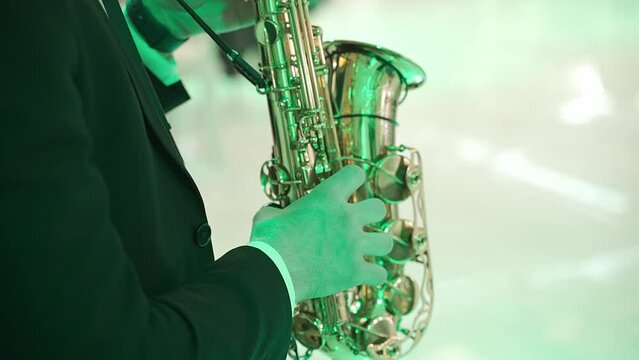 a musician in a black suit plays the saxophone in a banquet hall. performance during the ceremony. musical accompaniment of a festive event
