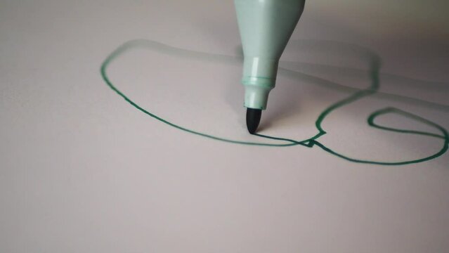 Green marker draws on a white sheet