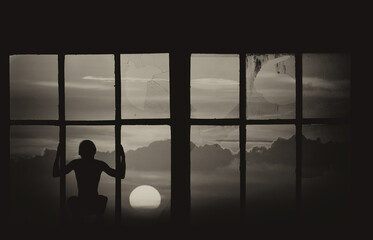 Silhouette of man crouching in the abandoned building looking at sunset through broken window in summer