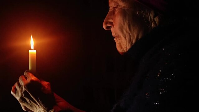 Destruction of the Ukrainian infrastructure. An old grandmother with a candle. An old grandmother without electricity. Russian aggression against Ukraine. De-energized Ukraine. War in Ukraine.