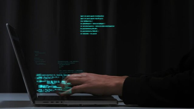 Pogrammer's hands quickly type computer code on a laptop keyboard. Hologram code shows up in different parts of the screen. Concept of programming and coding technologies. Timelapse footage