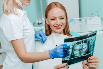 Obraz premium Doctor dentist and woman patient watching x-ray foto with teeth in stomatology clinic with medical equipment. Smile healthy teeth concept