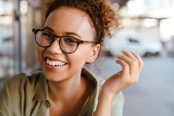 Hispanic woman in eyeglasses smiling while sitting at cafe