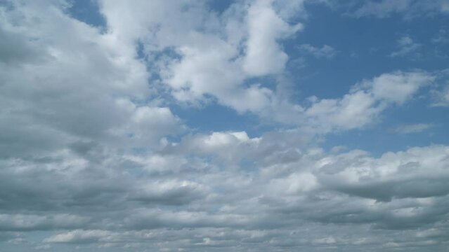 White puffy clouds forming on summer blue sky. Dark grey storm clouds. Timelapse.