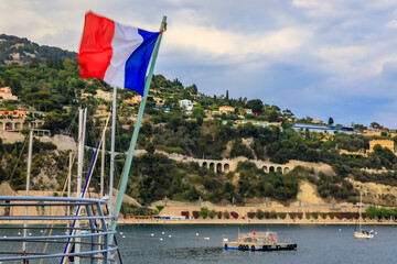 French flag with Mediterranean Sea and coastline in Villefranche sur Mer, France