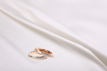 Wedding rings on white beige nacre wave fabric silk. Abstract texture horizontal copy space background.