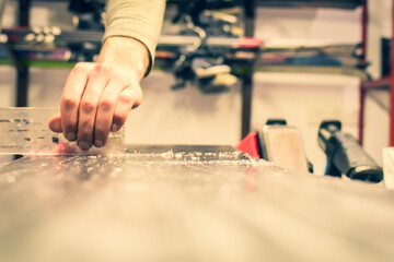 Repairman scrape wax off from snowboard with scraper in repair shop ski rental. Step by step guide