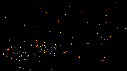 Particles of burning embers fly and glow isolated in the night sky. Natural yellow-hot sparks of fire on a black background, bright yellow bokeh from the fire.