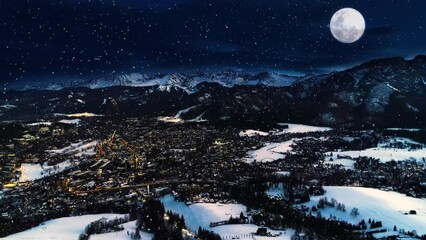 Snowy winter night, epic aerial view. Magical winter in the mountain village. Illuminated alpine city covered with snow. White mountains, ski resorts and big shining moon. Christmasy snowy landscape.